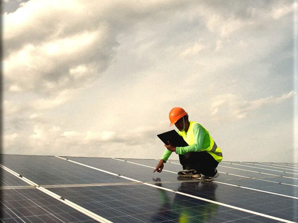 Technician inspecting solar panels on a PV installation